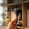 A hand holds a black silhouette of a wizard and staff, illuminating a warm lantern glow inside a wooden bookcase.