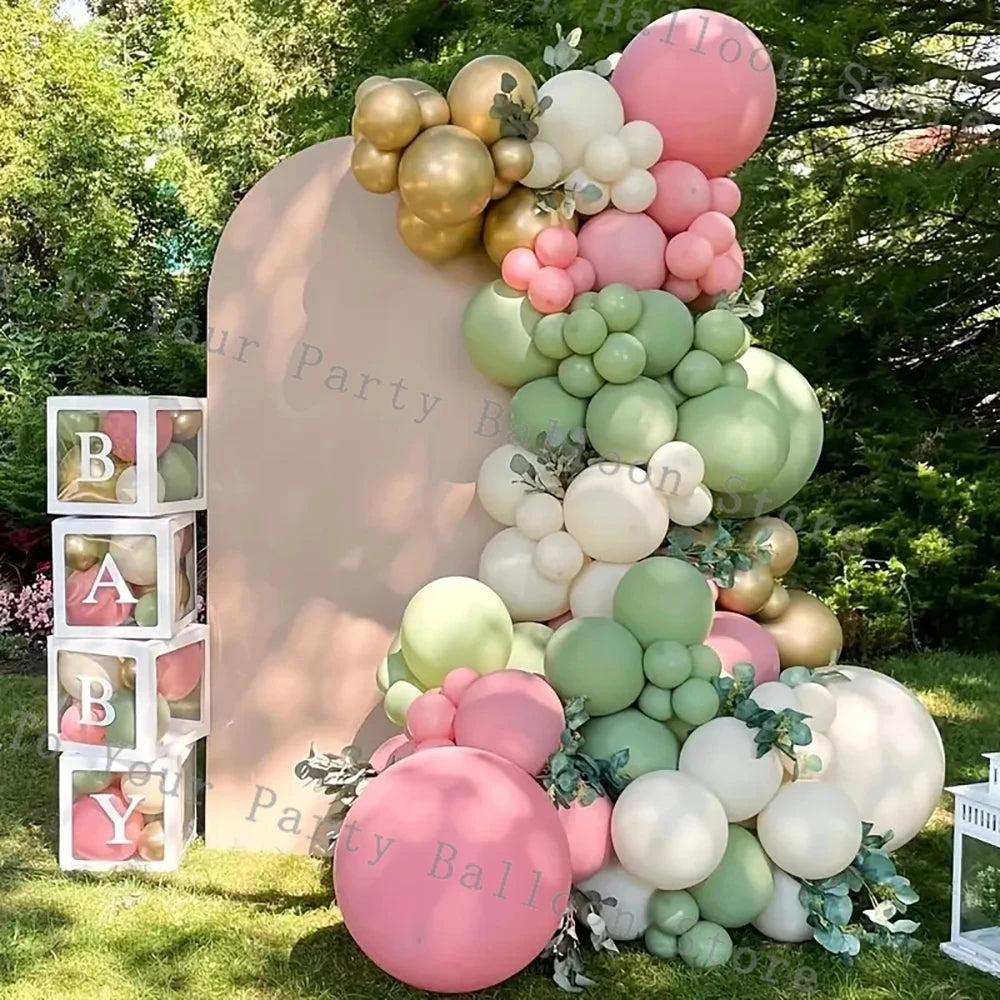 A balloon garland arch featuring pastel pink and white balloons set up outdoors against a light pink backdrop.