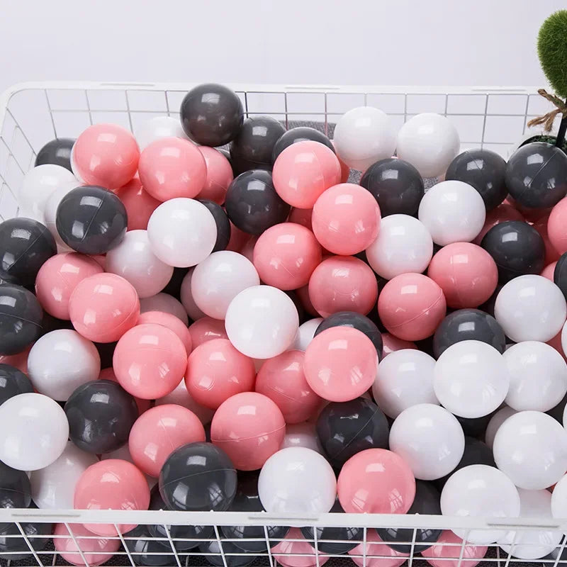 A large plastic basket filled with a variety of pink, white, and black spherical balls for play.