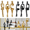 A set of abstract thinker sculptures in gold and black resin, displayed against a white background.
