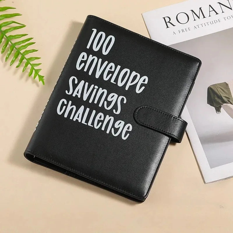 Black leather envelope savings challenge planner binder lying on a light surface.