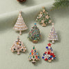 A collection of sparkling rhinestone Christmas tree brooches and pins in various sizes and greens