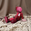 A pink Kawaii bear figurine with a detailed face and body is displayed on a beige knitted surface.