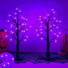 Zwei kahle Baumsilhouetten, beleuchtet mit lila LED-Licht vor einem violetten Hintergrund.