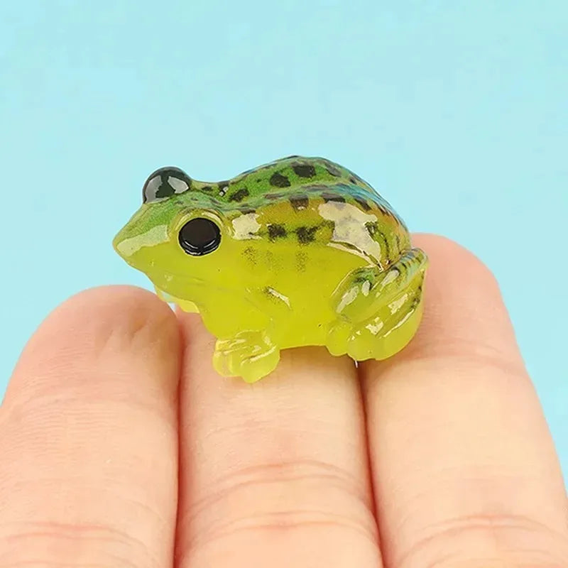 A bright green resin frog ornament with black eyes and speckled markings held in a person's hand.