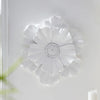 White flower-shaped resin wall art with layered petals mounted on a white wall.