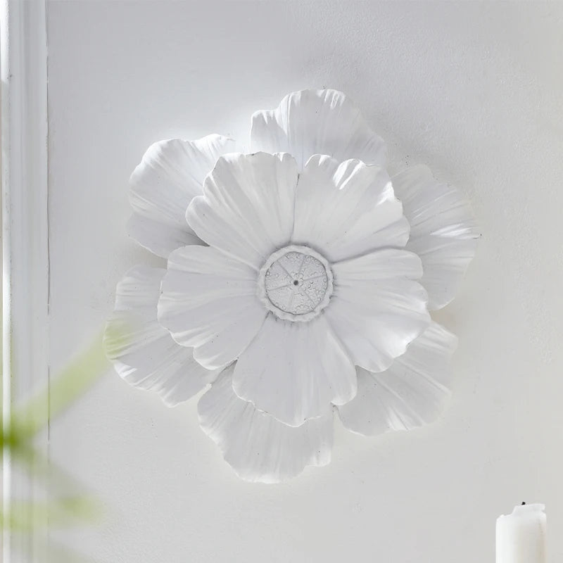 White flower-shaped resin wall art with layered petals mounted on a white wall.