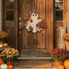 A wooden ghost door hanging with a witch hat design is displayed on a rustic wooden door surrounded by autumn foliage and pum