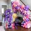 A large balloon arch featuring purple and pink balloons, a number eight, and decorative stars.