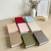 A collection of colorful laminated photo albums stacked on a wooden table.