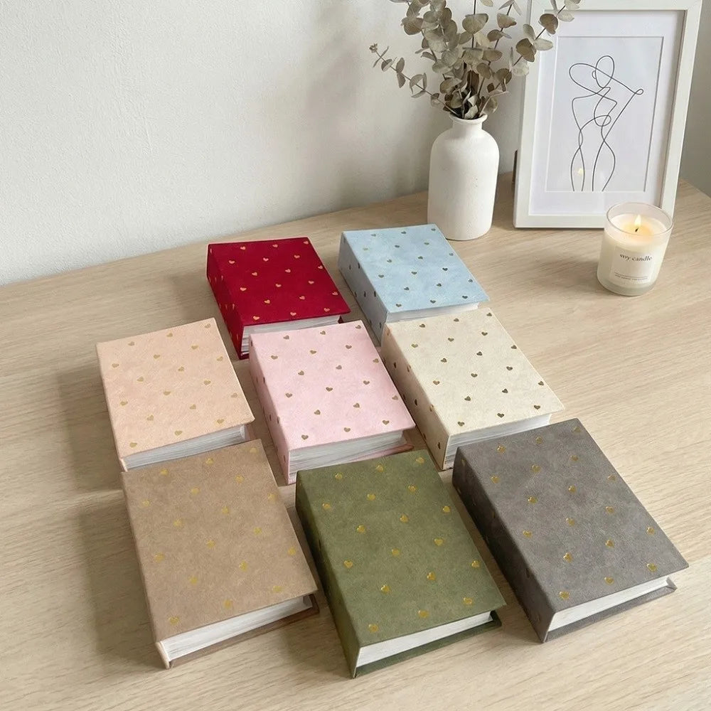 A collection of colorful laminated photo albums stacked on a wooden table.