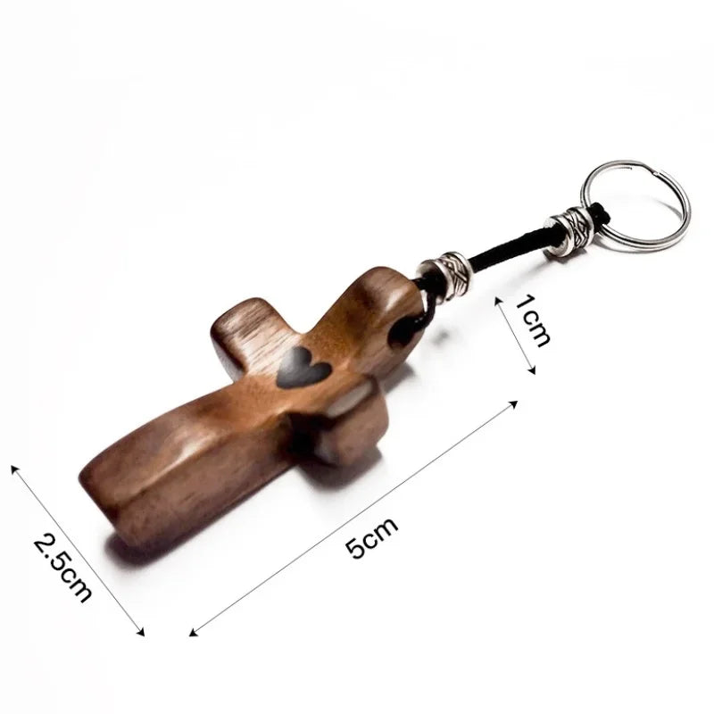 Handcrafted walnut cross keychain with a silver ring and black cord