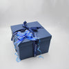 A dark blue gift box tied with a light blue ribbon and bow.