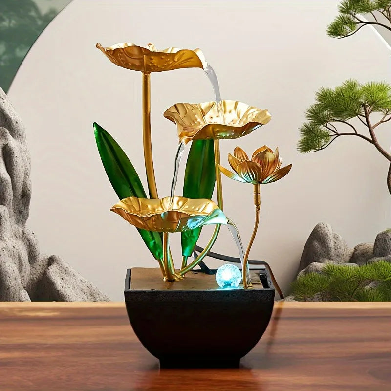 A golden lotus pond water fountain with green leaves and blue LED light set in a black bowl.