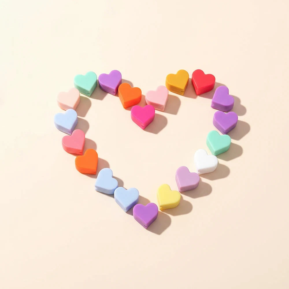 A collection of colorful silicone heart beads arranged in a heart shape on a light background.