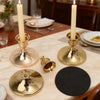 A set of vintage brass iron candlestick holders with tall white candles on a marble table.