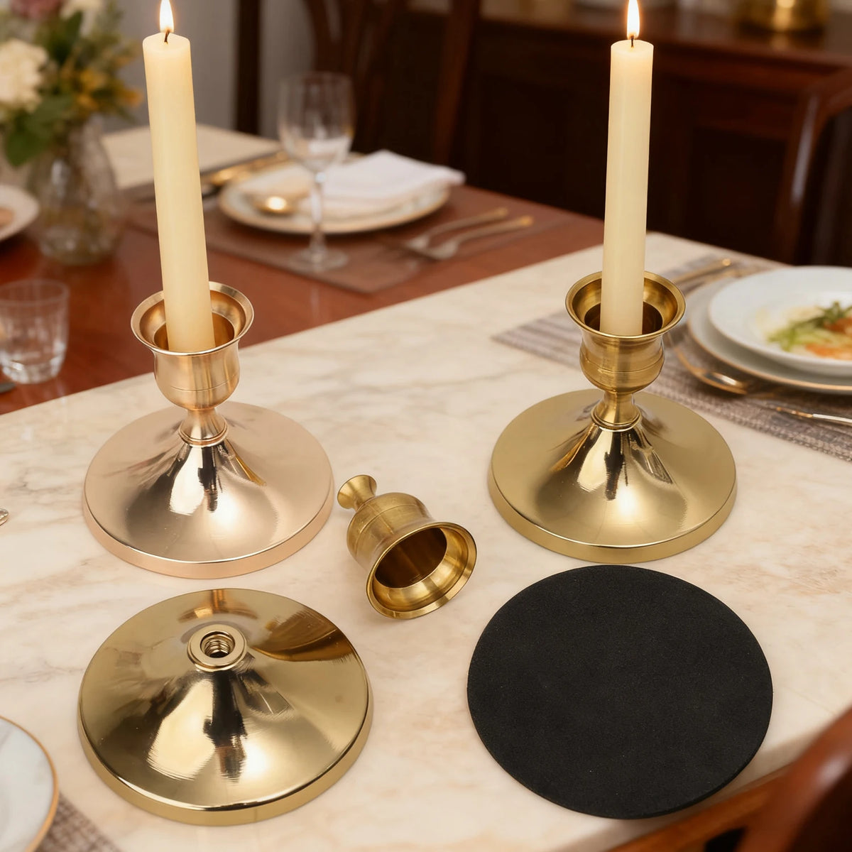 A set of vintage brass iron candlestick holders with tall white candles on a marble table.