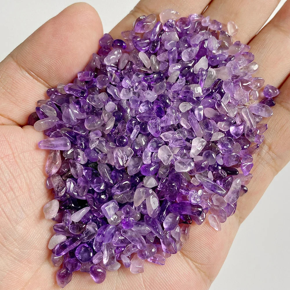 Una mano sostiene una pila de piedras de cuarzo amatista de color púrpura pulidas.