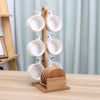 A ceramic coffee mug set with white mugs displayed on a wooden stand and stacked plates.