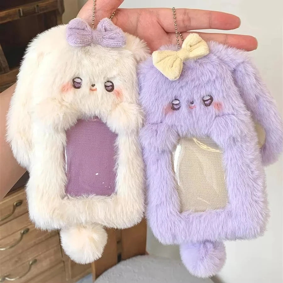Ein Paar flauschiger Cartoon-Plush-Fotokartenhalter in Weiß und Lavendel, gehalten von einer Hand.