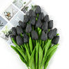 A bouquet of dark black artificial tulips with green leaves displayed on a white background.