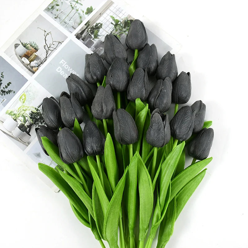 A bouquet of dark black artificial tulips with green leaves displayed on a white background.