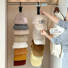 A hand is hanging a beige hat onto a 360 degree rotating hanger organizer for closet storage.