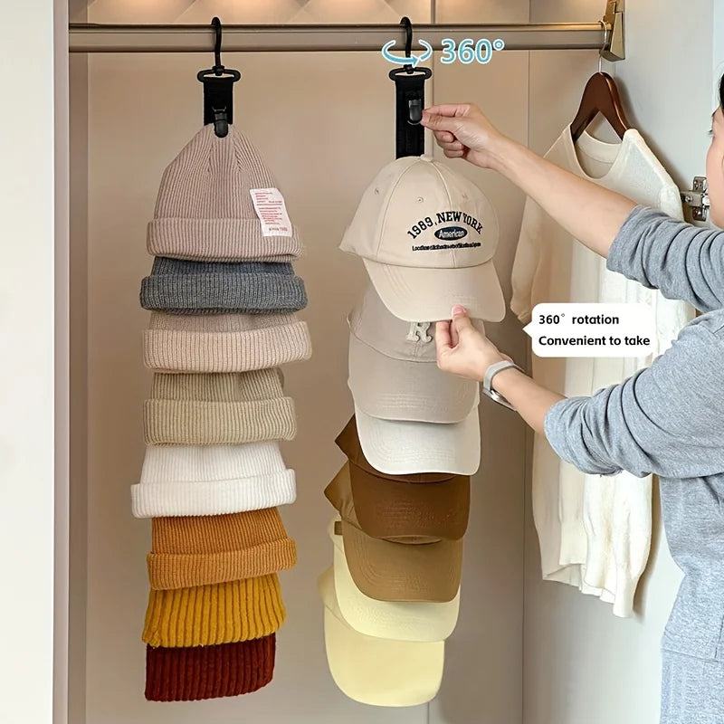 A hand is hanging a beige hat onto a 360 degree rotating hanger organizer for closet storage.