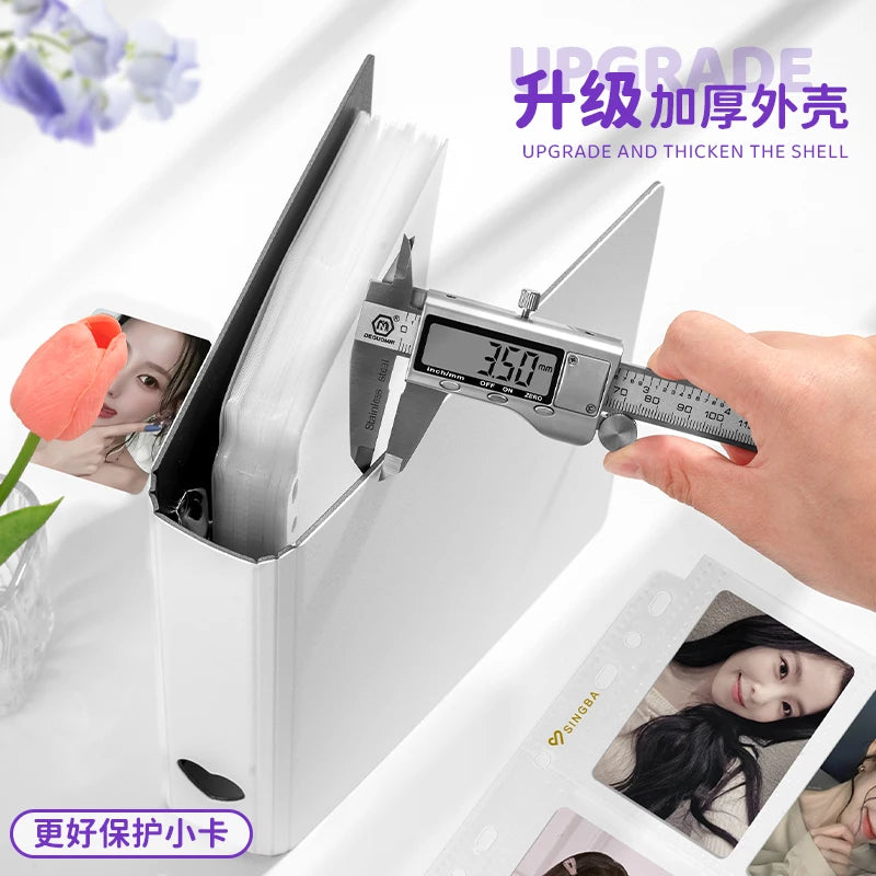 A hand is using a tool to upgrade and thicken the shell of a white ring binder designed for trading cards and photos.