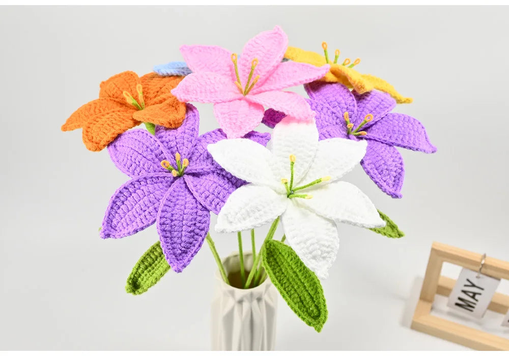 A hand-crocheted bouquet of colorful artificial lily flowers in shades of pink, orange, purple, and white.