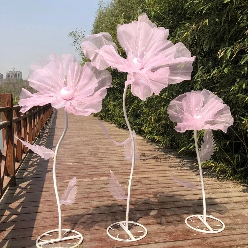 Three sheer pink velvet mesh flowers on white stems displayed outdoors