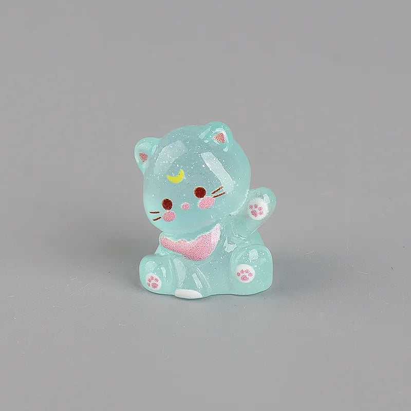 A small, translucent blue resin cat keychain with pink accents and glitter.