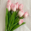 A bouquet of six pink and white artificial tulips with green stems on a white background.