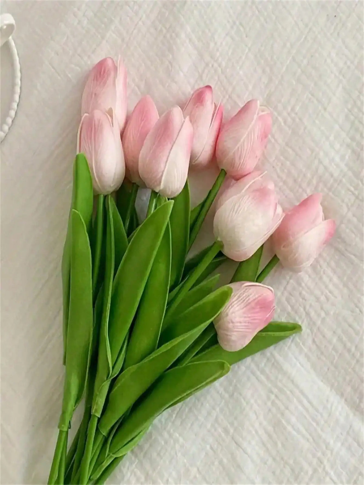 A bouquet of six pink and white artificial tulips with green stems on a white background.