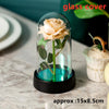 An artificial rose flower is displayed inside a glass dome on a black base.