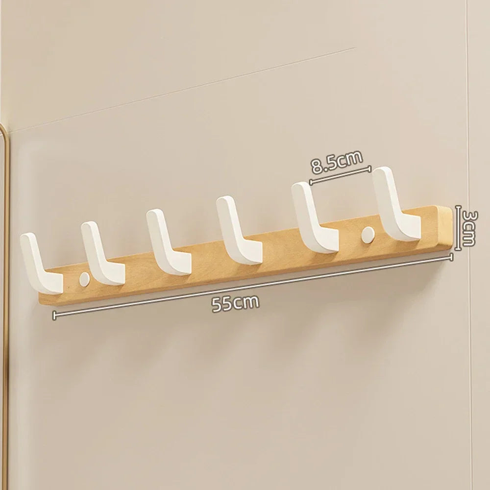 A walnut wood coat rack with eight white hooks and a storage shelf mounted on a wall.