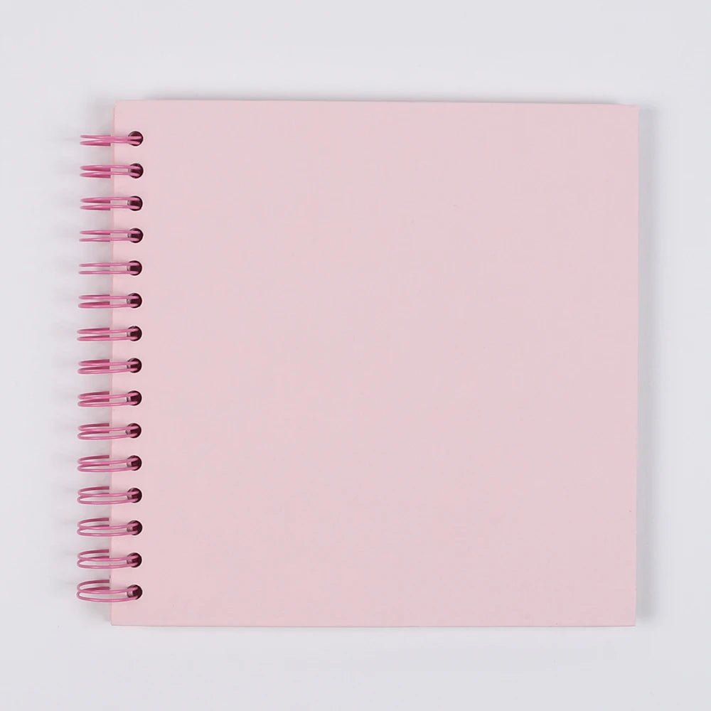 A blank pink spiral-bound kraft paper scrapbook for DIY memory keeping.
