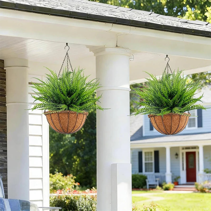 Künstliches Boston-Fern-grünes Busch in einem geflochtenen Korb, der von einer Veranda-Säule hängt