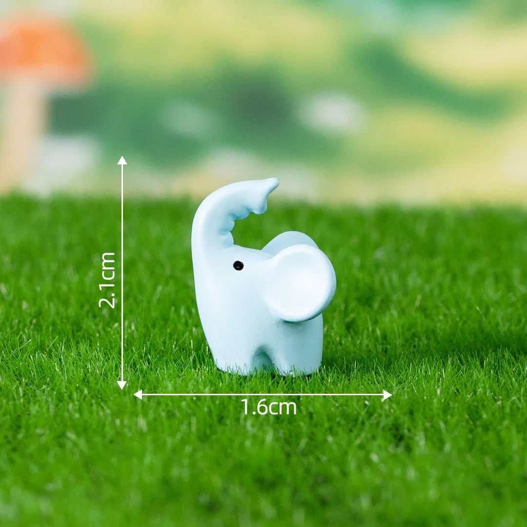 A small, light blue elephant figurine is placed on green grass with measurement lines.