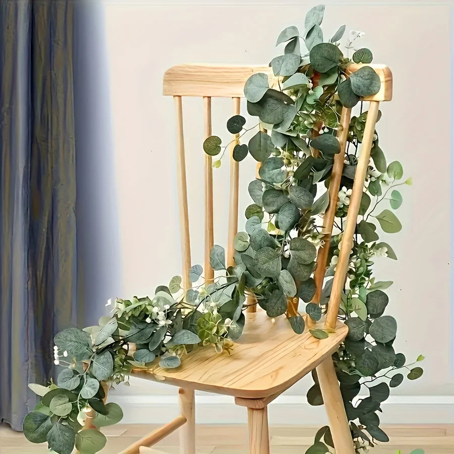 A wooden chair decorated with a lush green artificial eucalyptus wreath garland.