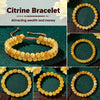 A close-up of a yellow citrine crystal beaded bracelet worn on a wrist, displayed against a dark green background.