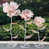 A set of three large pink velvet mesh flowers on white stems used for wedding decoration.