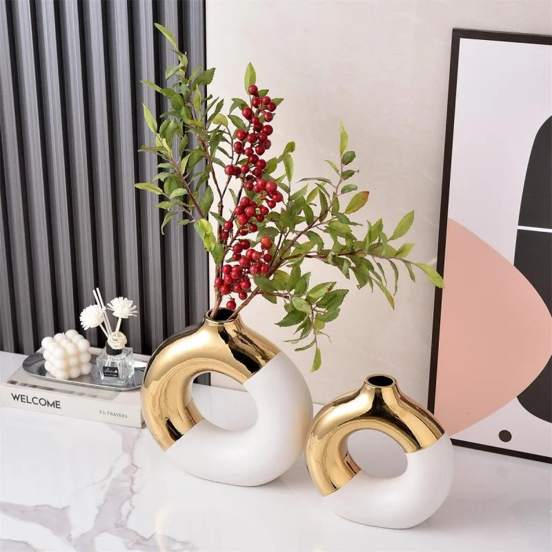 A display of luxury ceramic flower vases featuring gold and white finishes with green foliage.