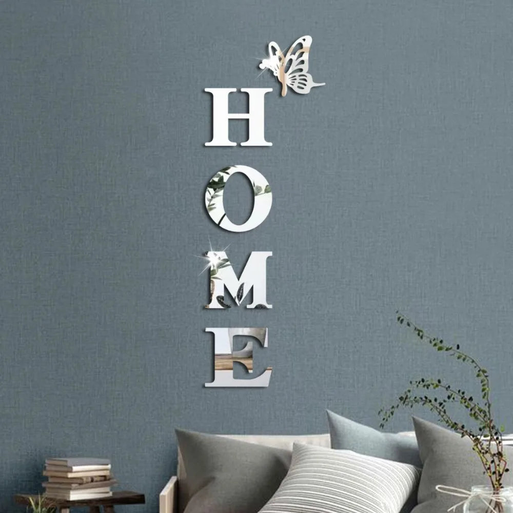Silver acrylic wall stickers spelling out HOME with a butterfly design on a gray wall.