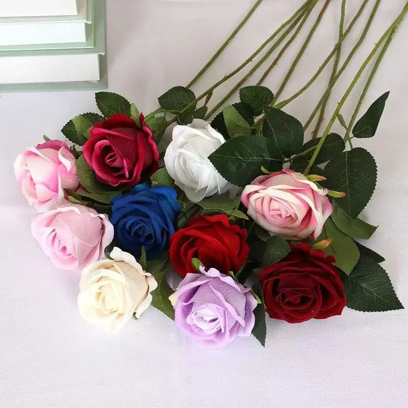 A bouquet of realistic velvet artificial roses in shades of pink, red, white, and purple with green leaves.