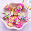A pink dish filled with colorful candy resin cabochons in various swirls of pink, yellow, and green.