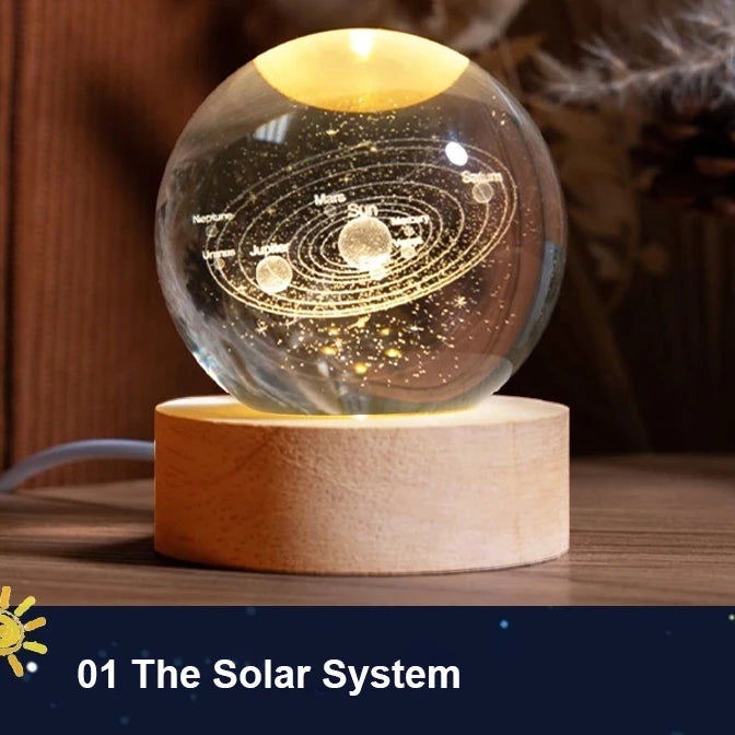 A glass crystal ball night light showing the solar system with planets and the sun, resting on a wooden base.