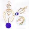 A gold and purple Turkish blue eye amulet horseshoe wall hanging featuring an elephant charm.