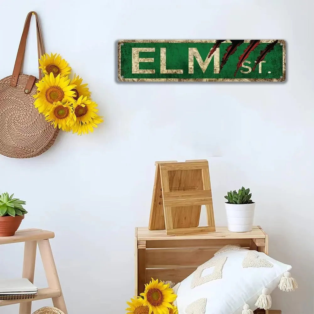 A vintage metal tin sign with the text ELM Str. in green lettering mounted on a white wall.