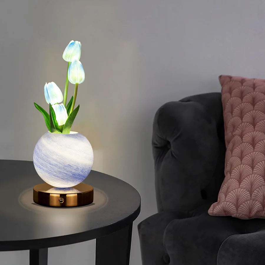 A white tulip LED night light with blue accents sits on a dark table.